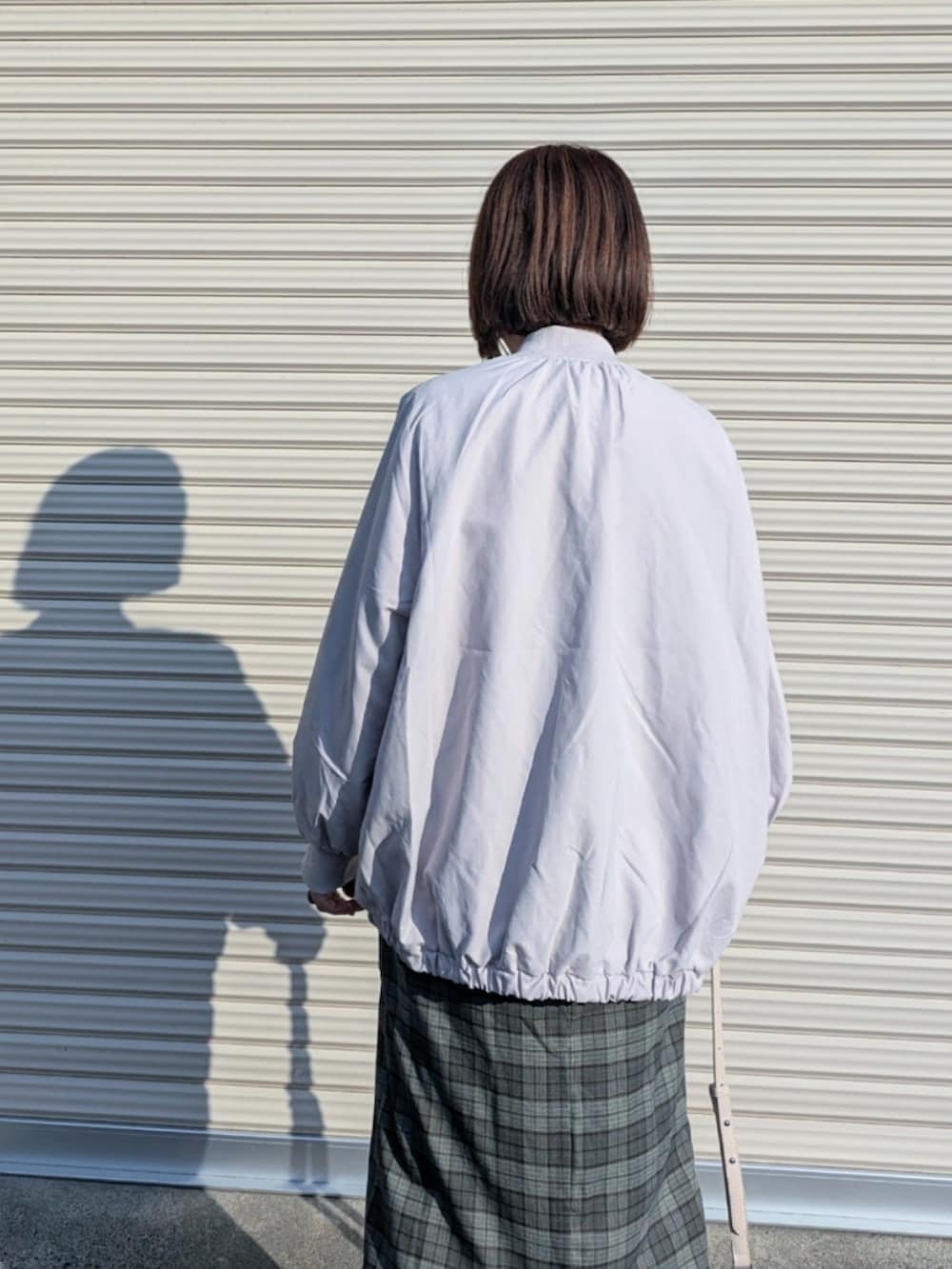 グレー系のブルゾン、ホワイト系のシャツ/ブラウス、ブラック系のベストを着用したレディースの秋コーディネートの3枚目の写真