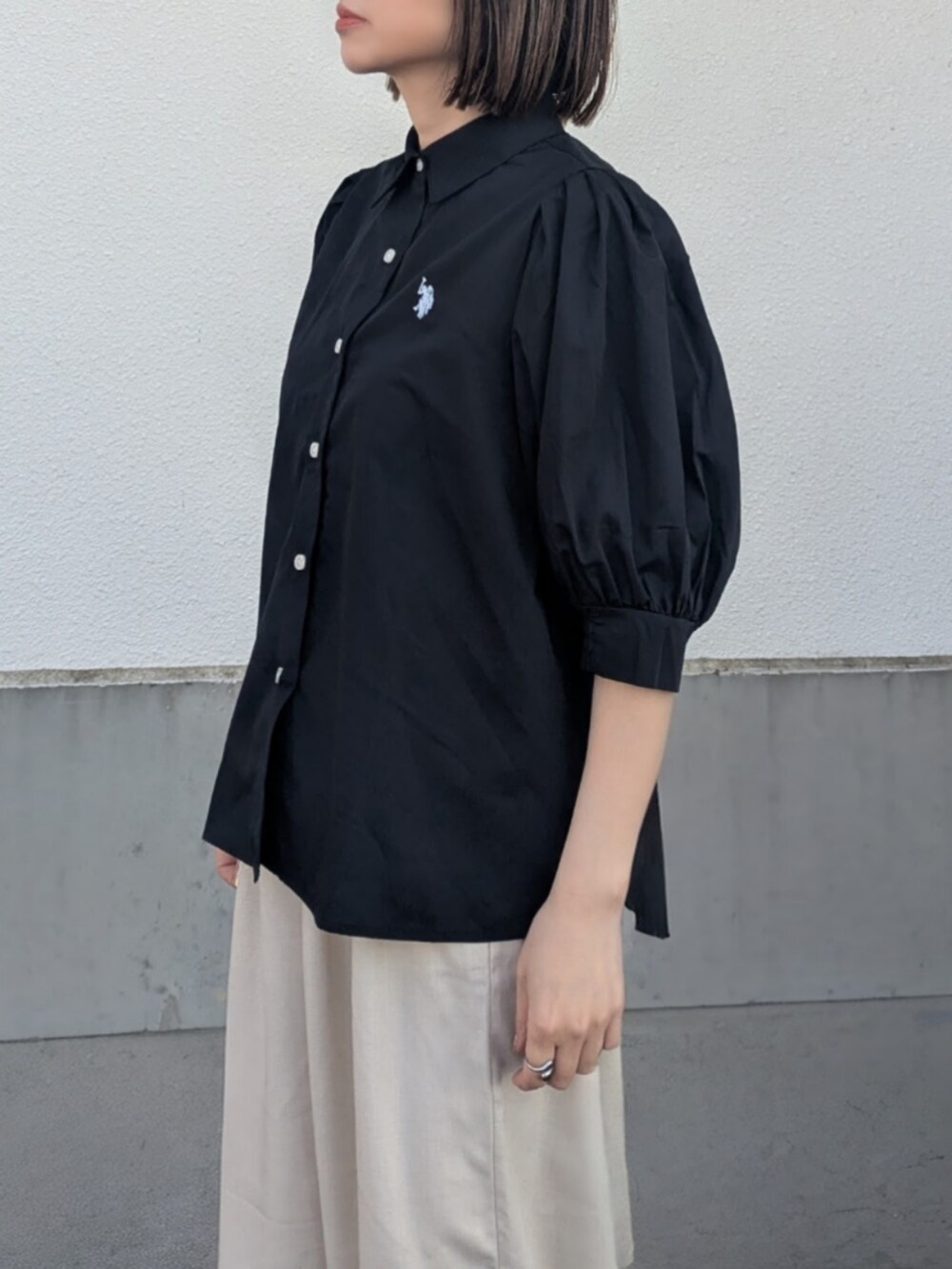 ブラック系のシャツ/ブラウス、ベージュ系のスラックス、ブラック系のパンプスを着用したレディースの春コーディネートの3枚目の写真