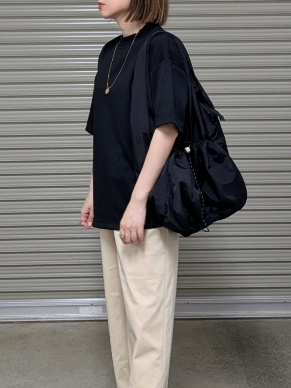 ブラック系のTシャツ/カットソー、ブラック系のトートバッグ、ブラック系のサンダルを着用したレディースの夏コーディネートの3枚目の写真