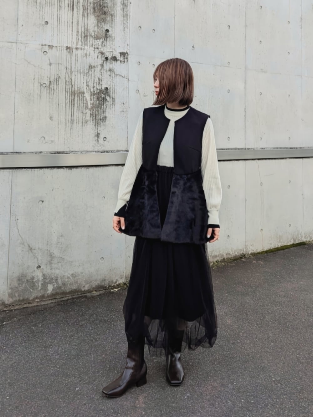 ブラック系のベスト、ホワイト系のニット/セーター、ベージュ系のショルダーバッグを着用したレディースの秋コーディネートの5枚目の写真