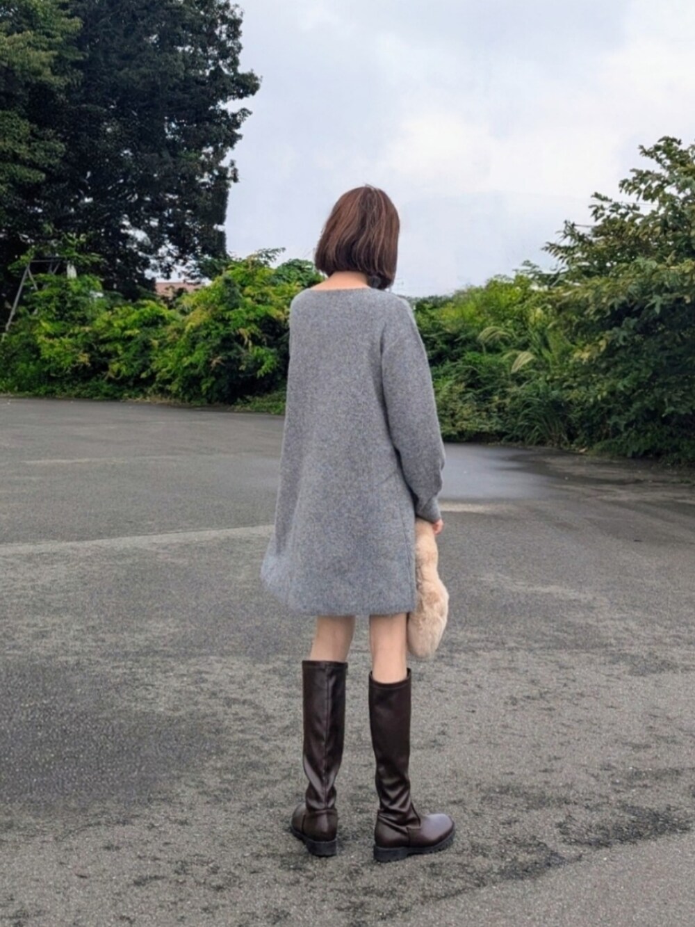 グレー系のワンピース、ブラウン系のブーツ、ベージュ系のハンドバッグを着用したレディースの秋コーディネートの3枚目の写真