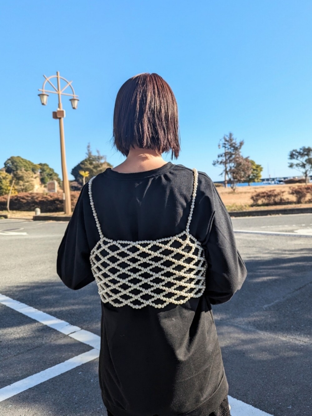 ホワイト系のベスト、ブラック系のTシャツ/カットソー、ホワイト系のショルダーバッグを着用したレディースの冬コーディネートの2枚目の写真