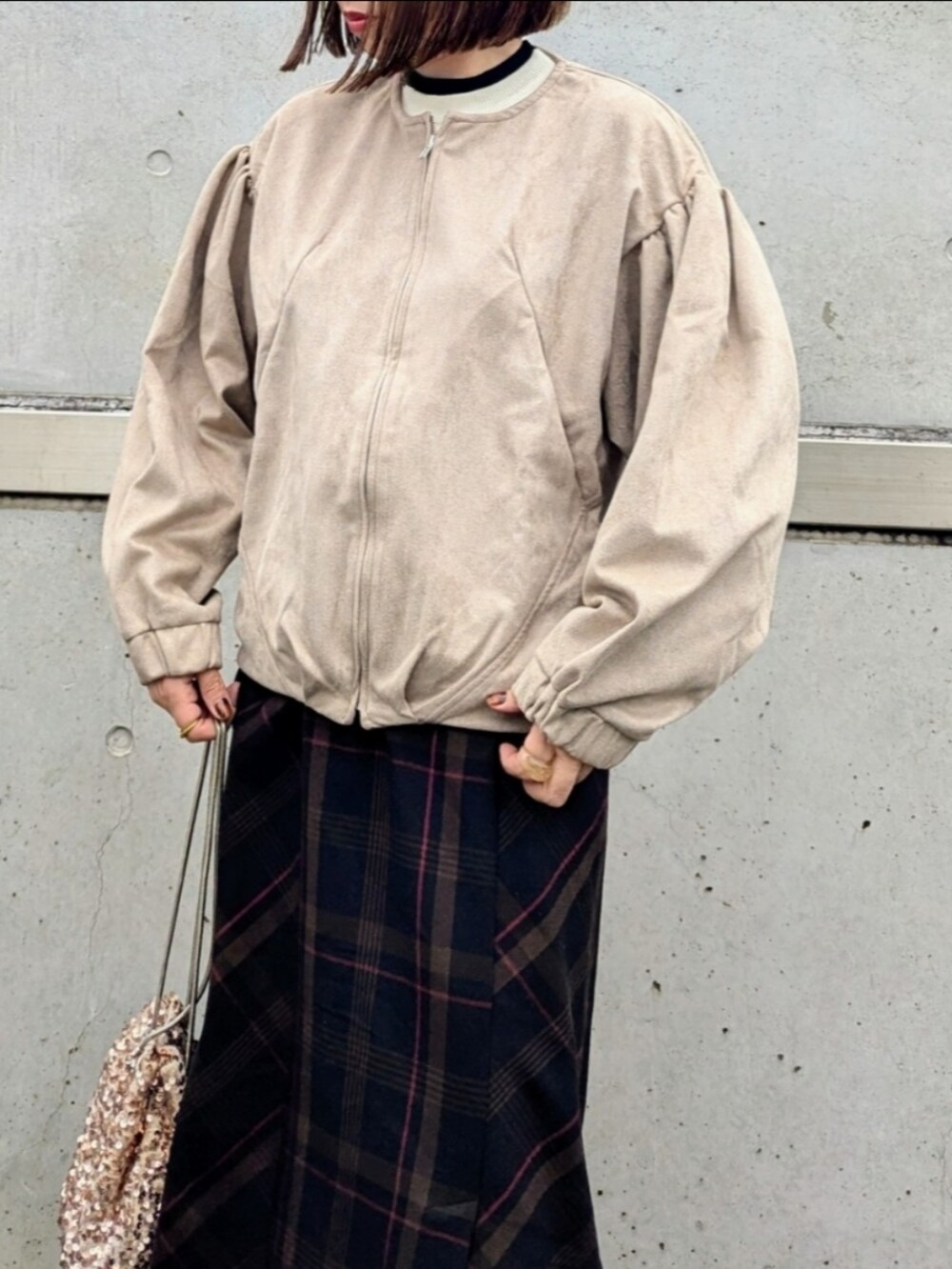 ベージュ系のブルゾン、ホワイト系のニット/セーター、ベージュ系のショルダーバッグを着用したレディースの秋コーディネートの4枚目の写真