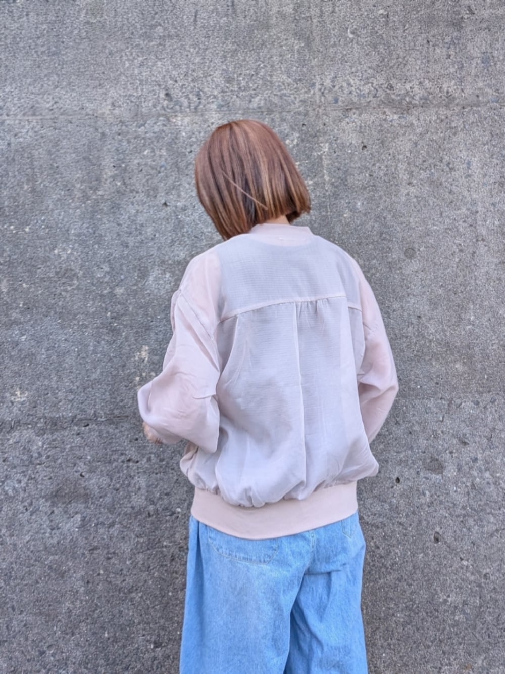 ベージュ系のブルゾン、ブルー系のデニムパンツ、ブラック系のタンクトップを着用したレディースの春コーディネートの4枚目の写真