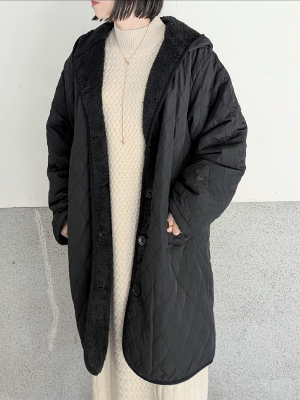 ブラック系のナイロンジャケット、ホワイト系のワンピース、シルバー系のショルダーバッグを着用したレディースの冬コーディネートの2枚目の写真