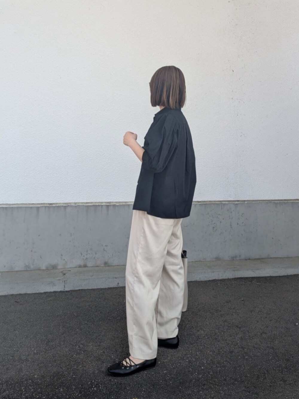 ブラック系のシャツ/ブラウス、ベージュ系のスラックス、ブラック系のパンプスを着用したレディースの春コーディネートの4枚目の写真