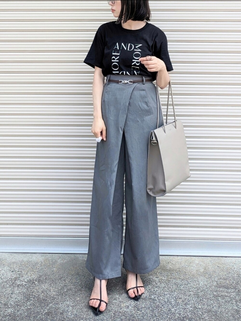 ブラック系のTシャツ/カットソー、グレー系のスラックス、グレー系のトートバッグを着用したレディースの夏コーディネートの2枚目の写真