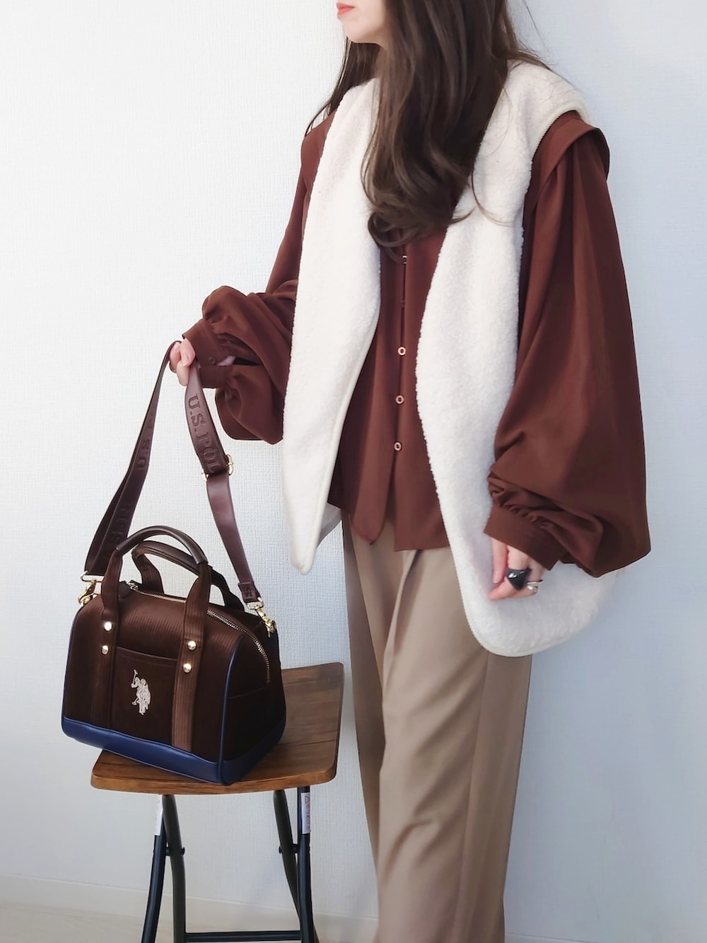 ブラウン系のボストンバッグ、ホワイト系のベスト、ベージュ系のセットアップを着用したレディースの秋コーディネートの3枚目の写真