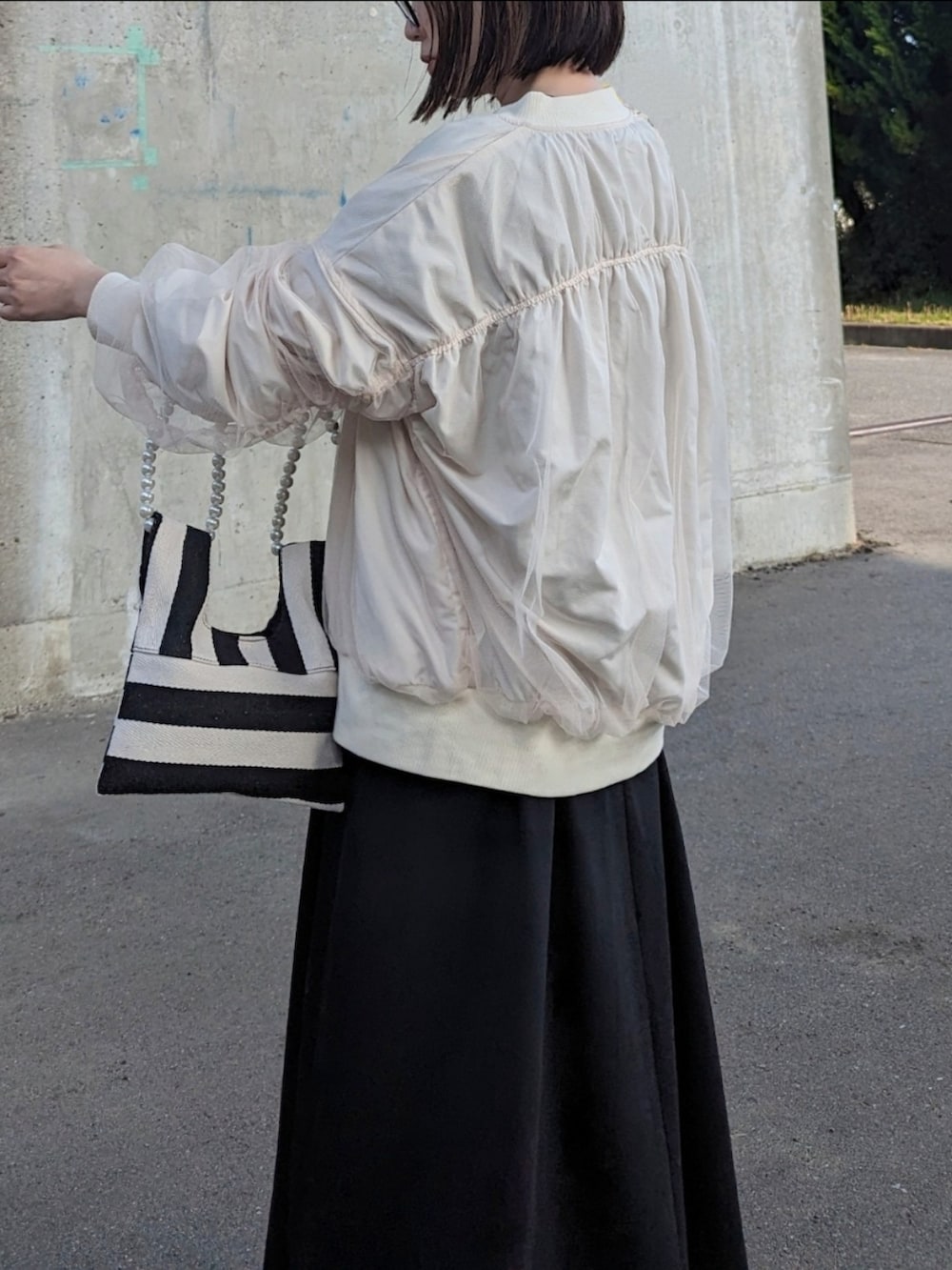 ホワイト系のブルゾン、ブラック系のワンピース、ホワイト系のショルダーバッグを着用したレディースの春コーディネートの4枚目の写真