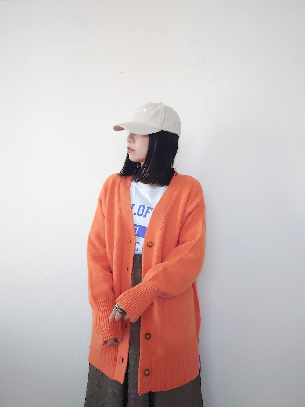ホワイト系のTシャツ/カットソー、オレンジ系のカーディガン/ボレロ、ベージュ系のスニーカーを着用したレディースの秋コーディネートの2枚目の写真