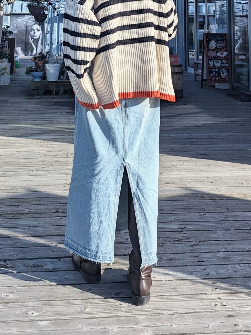 ブルー系のスカート、ホワイト系のニット/セーター、シルバー系のバッグを着用したレディースの春コーディネートの3枚目の写真