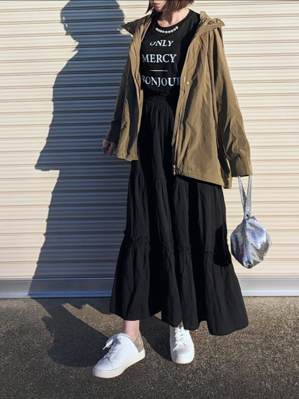 グリーン系のマウンテンパーカー、ブラック系のTシャツ/カットソー、ホワイト系のスニーカーを着用したレディースの冬コーディネートの2枚目の写真