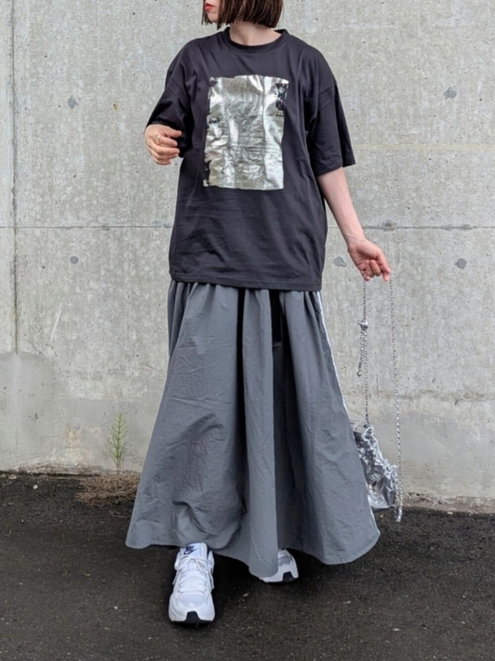 ブラック系のTシャツ/カットソー、グレー系のスカート、シルバー系のショルダーバッグを着用したレディースの夏コーディネートの2枚目の写真