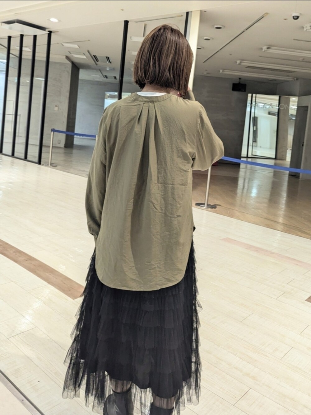 グリーン系のシャツ/ブラウス、ホワイト系のTシャツ/カットソー、ブラック系のブーツを着用したレディースの秋コーディネートの3枚目の写真