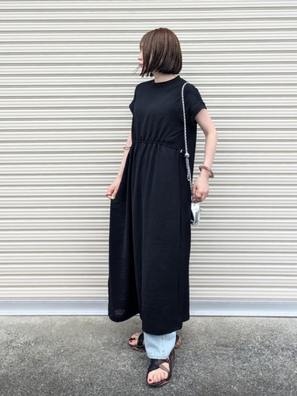 ブラック系のワンピース、ブルー系のデニムパンツ、シルバー系のショルダーバッグを着用したレディースの夏コーディネートの2枚目の写真