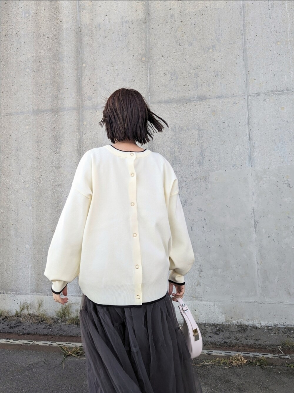 ホワイト系のカーディガン/ボレロ、ホワイト系のハンドバッグ、グレー系のスカートを着用したレディースの冬コーディネートの2枚目の写真