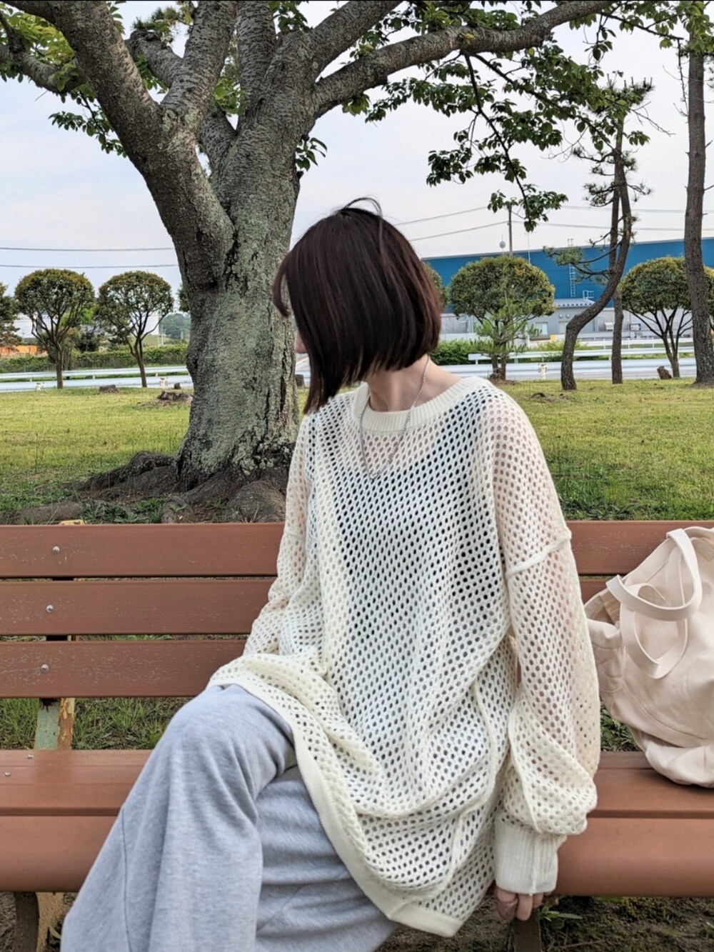 ホワイト系のニット/セーター、グレー系のスウェットパンツ、ベージュ系のショルダーバッグを着用したレディースの春コーディネートの3枚目の写真