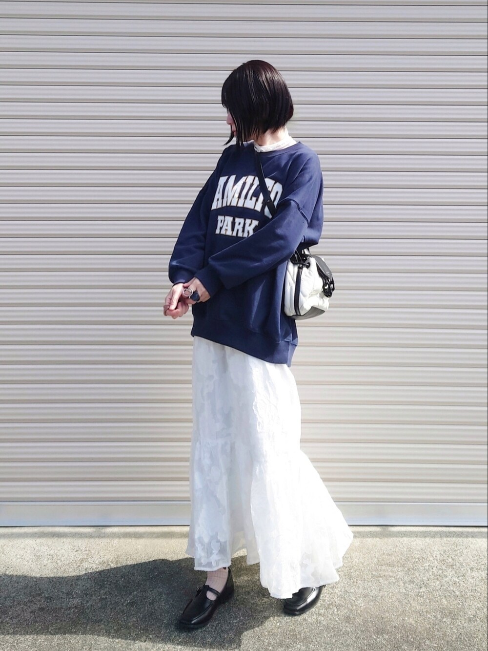 ブルー系のスウェット、ホワイト系のショルダーバッグ、ホワイト系のスカートを着用したレディースの冬コーディネートの2枚目の写真