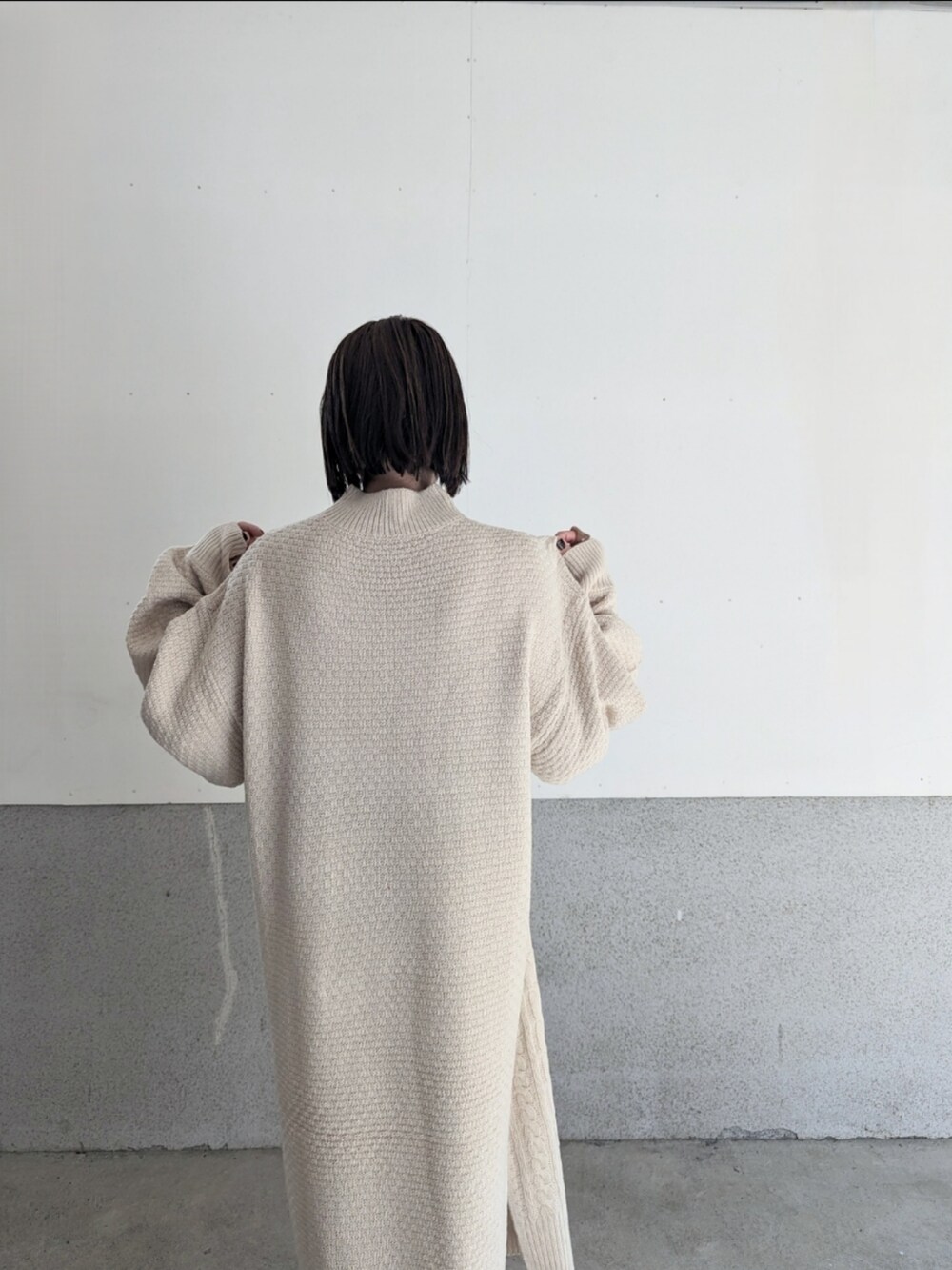 ホワイト系のワンピース、グレー系のベスト、ホワイト系のハンドバッグを着用したレディースの秋コーディネートの3枚目の写真