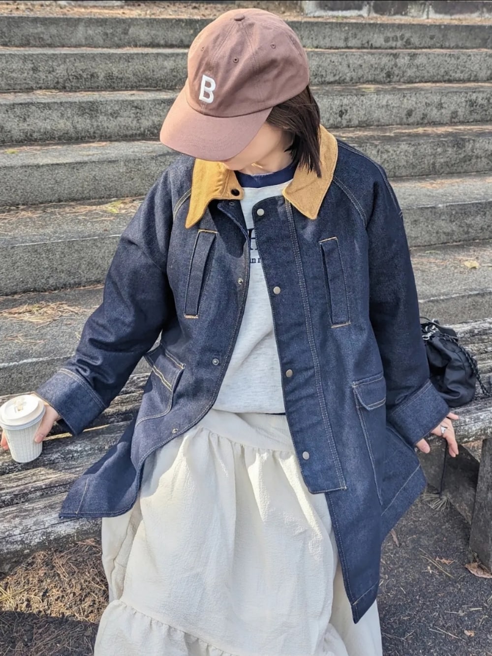 ブルー系のデニムジャケット、ベージュ系のスウェット、ブラック系のショルダーバッグを着用したレディースの冬コーディネートの2枚目の写真