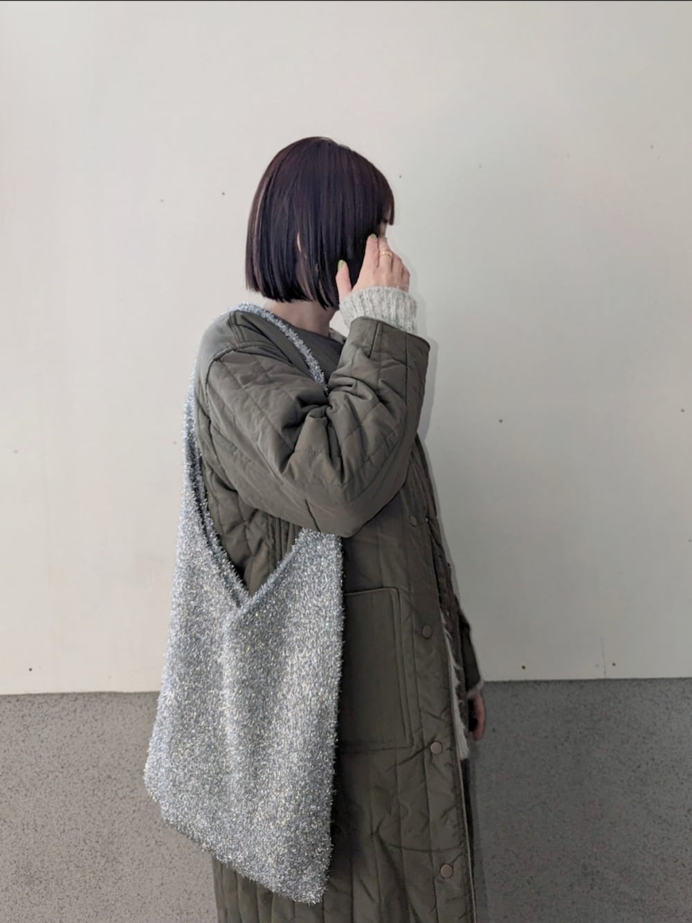 グリーン系のノーカラージャケット、グレー系のニット/セーター、シルバー系のショルダーバッグを着用したレディースの冬コーディネートの2枚目の写真