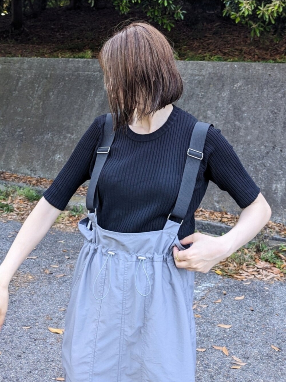 ブラック系のニット/セーター、グレー系のジャンパースカート、ブラウン系のサンダルを着用したレディースの夏コーディネートの3枚目の写真