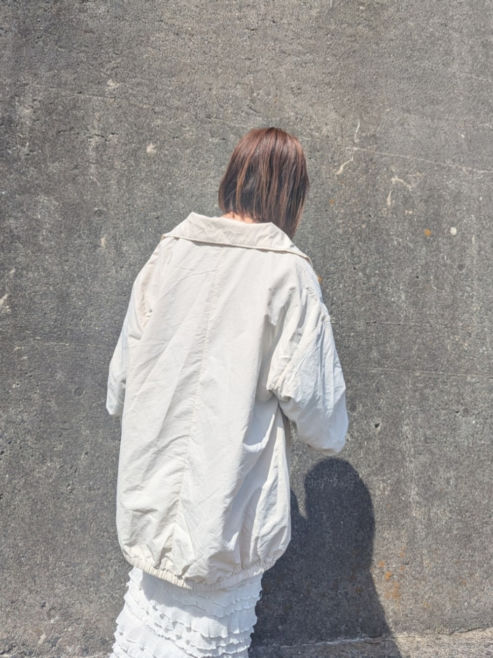 ホワイト系のナイロンジャケット、グリーン系のスウェット、ホワイト系のスカートを着用したレディースの春コーディネートの4枚目の写真