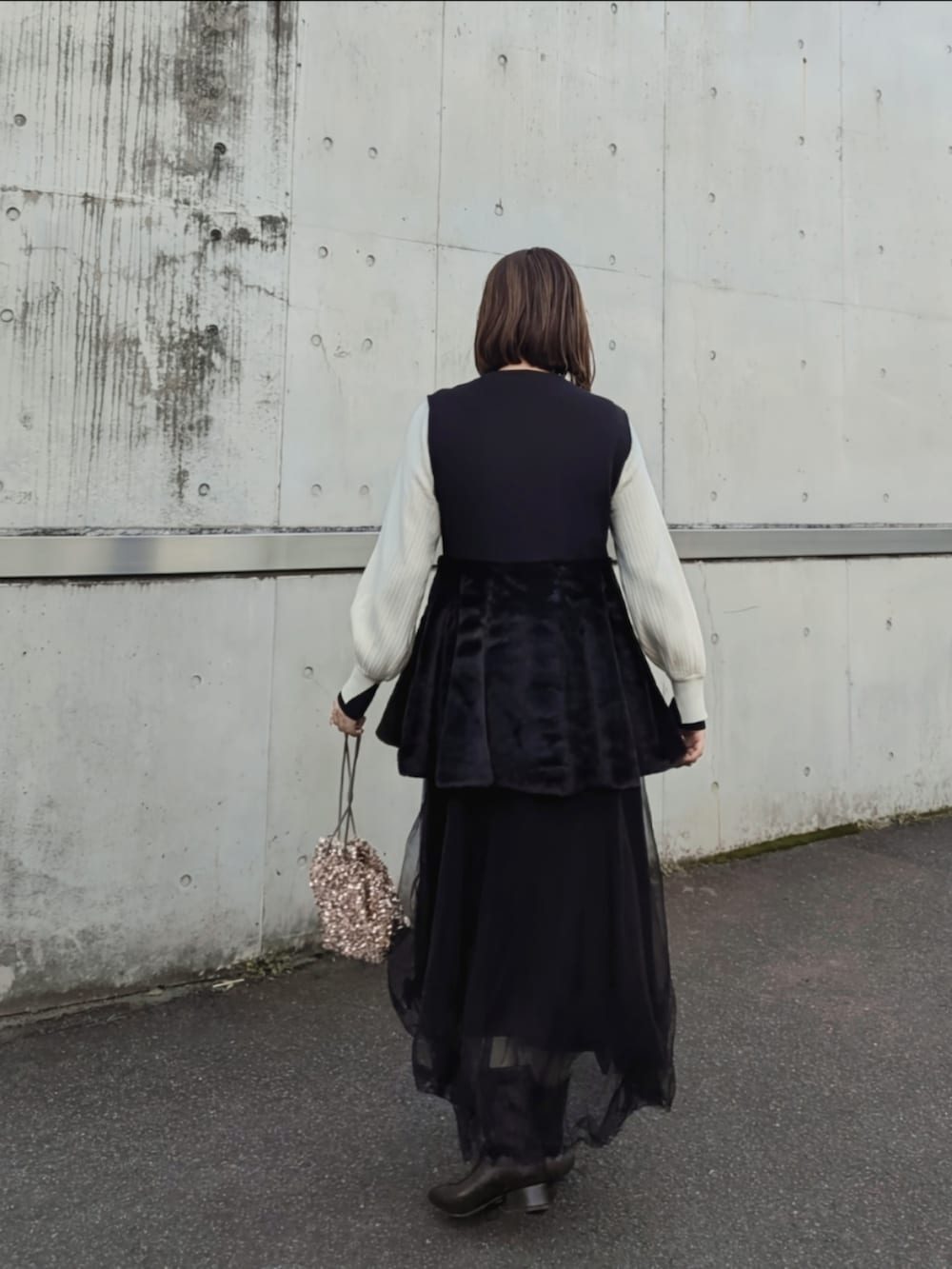 ブラック系のベスト、ホワイト系のニット/セーター、ベージュ系のショルダーバッグを着用したレディースの秋コーディネートの3枚目の写真