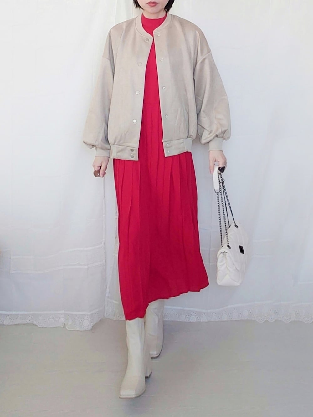 ベージュ系のスタジャン、レッド系のワンピース、ホワイト系のショルダーバッグを着用したレディースの春コーディネートの2枚目の写真