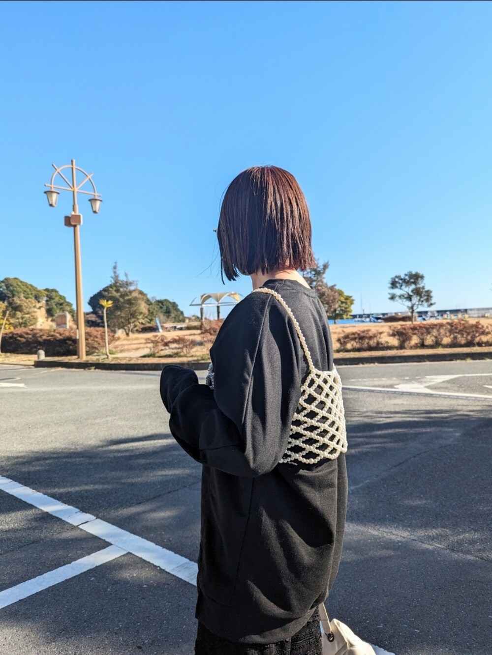 ホワイト系のベスト、ブラック系のTシャツ/カットソー、ホワイト系のショルダーバッグを着用したレディースの冬コーディネートの3枚目の写真