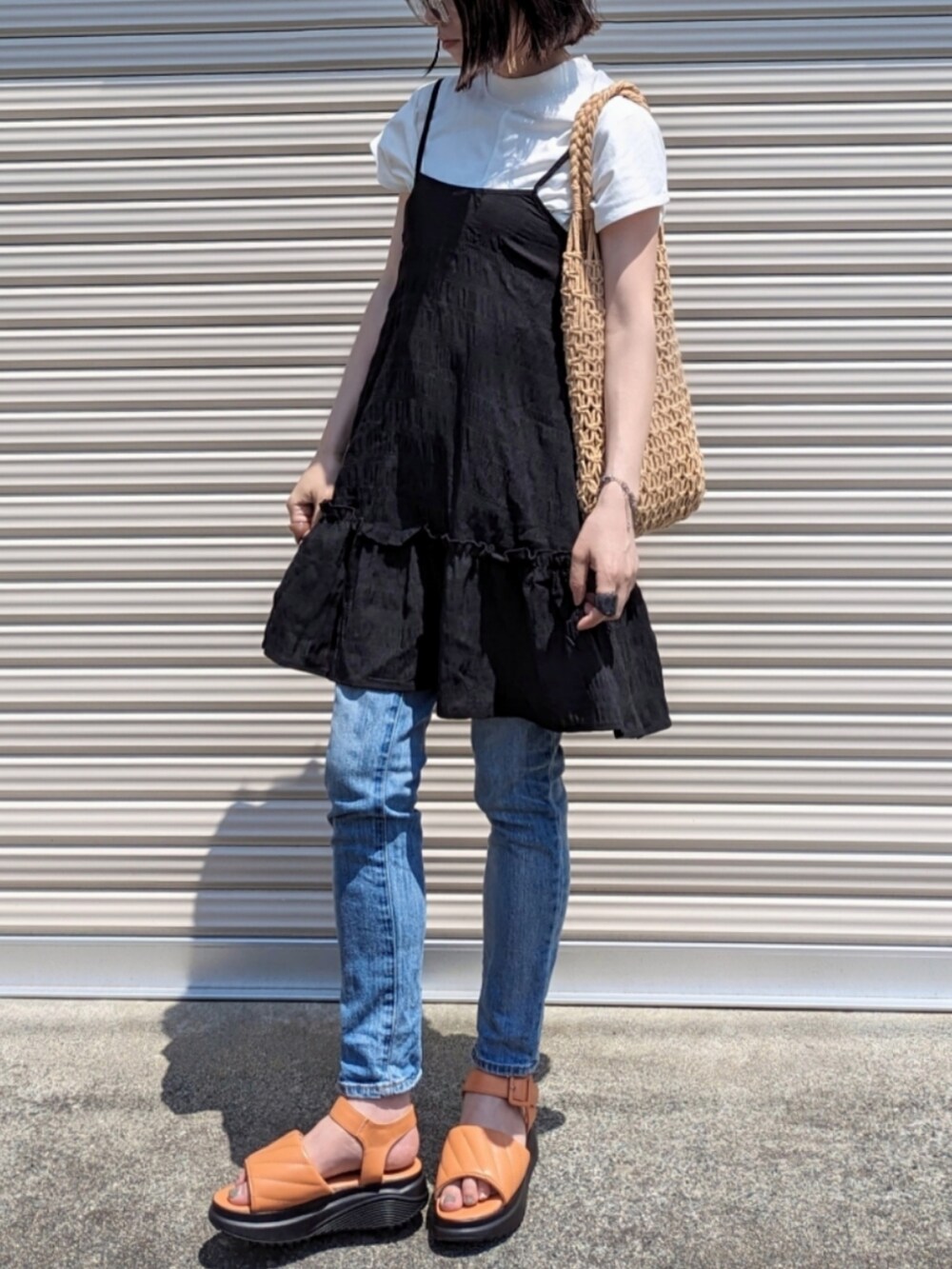 ブラウン系のかごバッグ、オレンジ系のサンダル、ブルー系のデニムパンツを着用したレディースの夏コーディネートの2枚目の写真