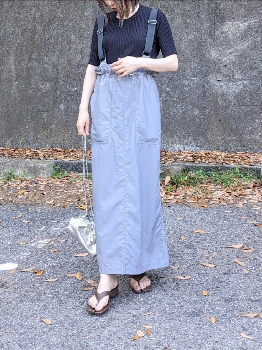 ブラック系のニット/セーター、グレー系のジャンパースカート、ブラウン系のサンダルを着用したレディースの夏コーディネートの2枚目の写真