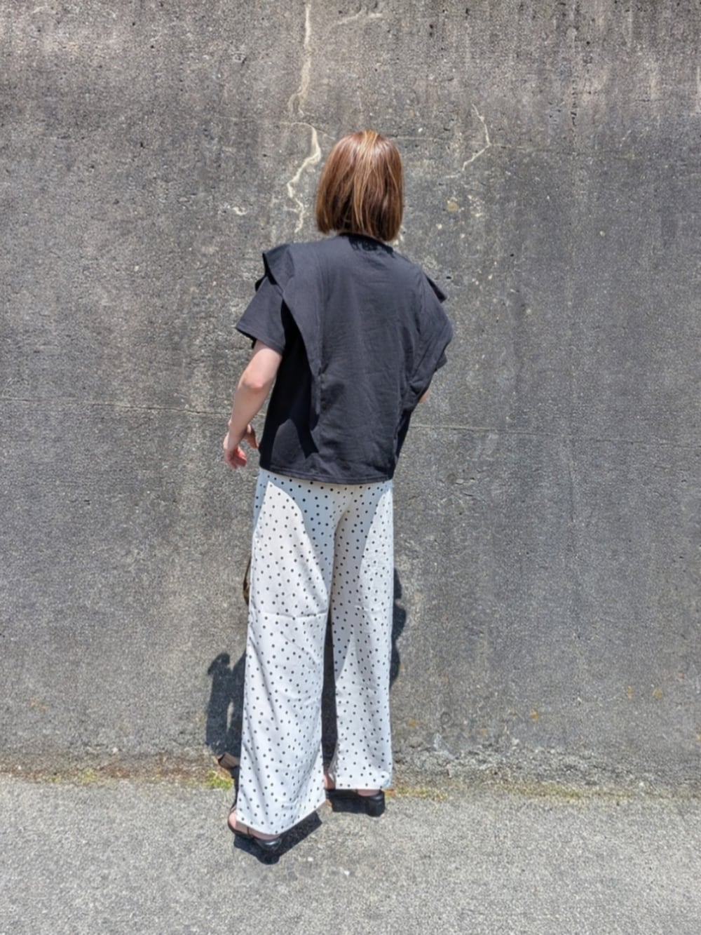 ブラック系のTシャツ/カットソー、ブラック系のサンダル、ブラウン系のショルダーバッグを着用したレディースの夏コーディネートの3枚目の写真