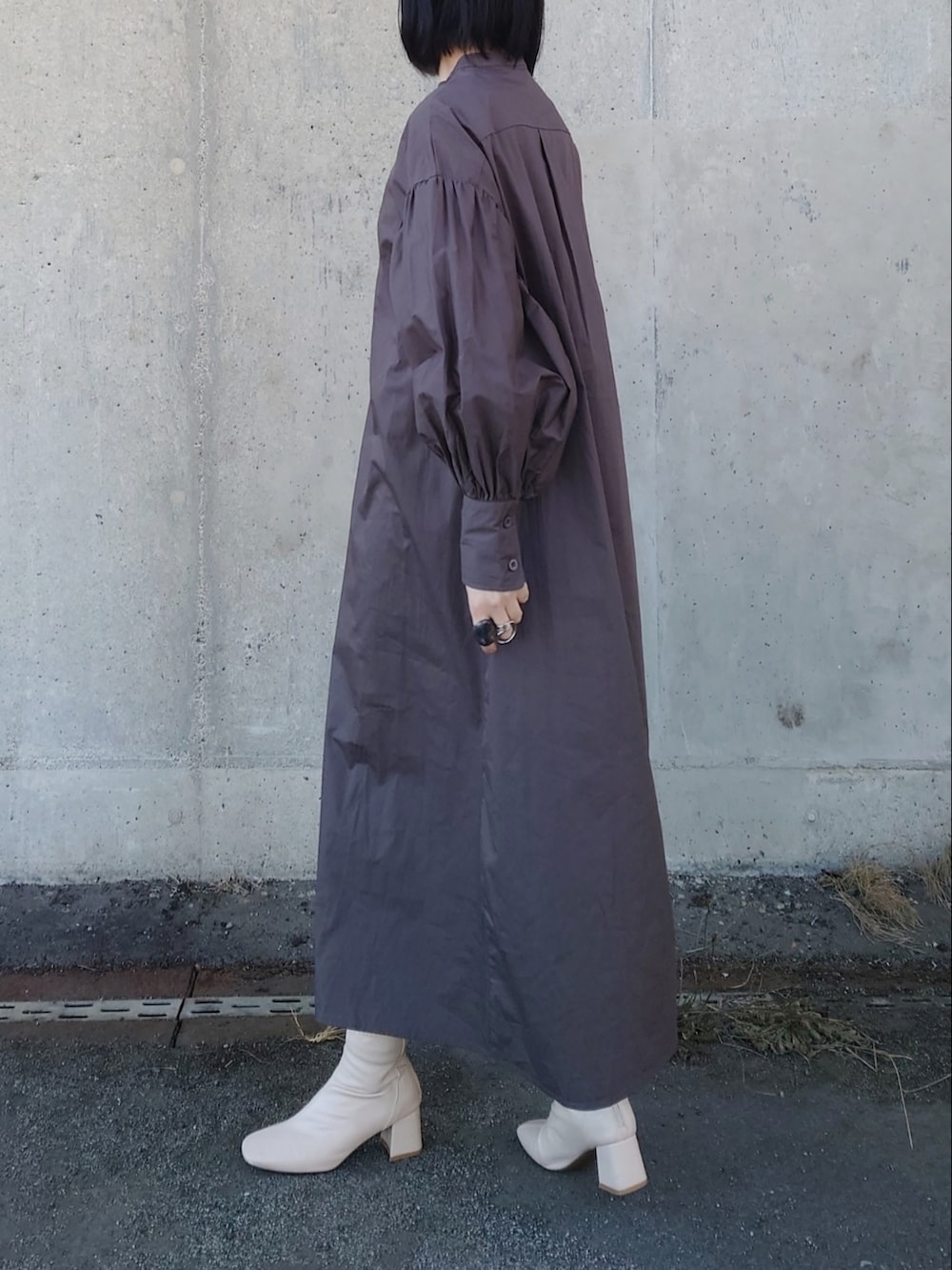 グレー系のワンピース、ホワイト系のブーツ、ベージュ系のショルダーバッグを着用したレディースの春コーディネートの2枚目の写真