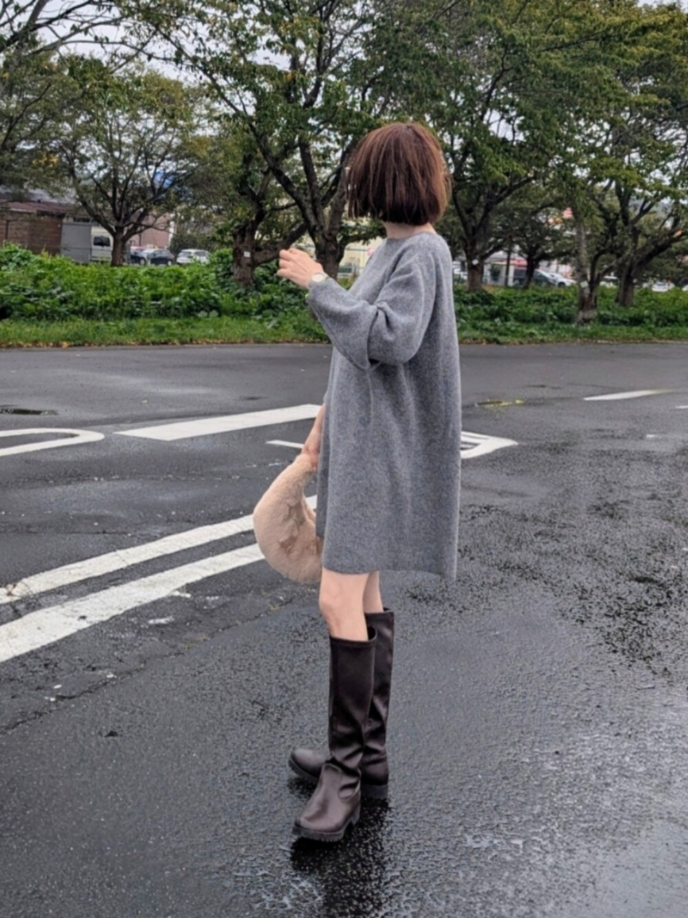 グレー系のワンピース、ブラウン系のブーツ、ベージュ系のハンドバッグを着用したレディースの秋コーディネートの2枚目の写真