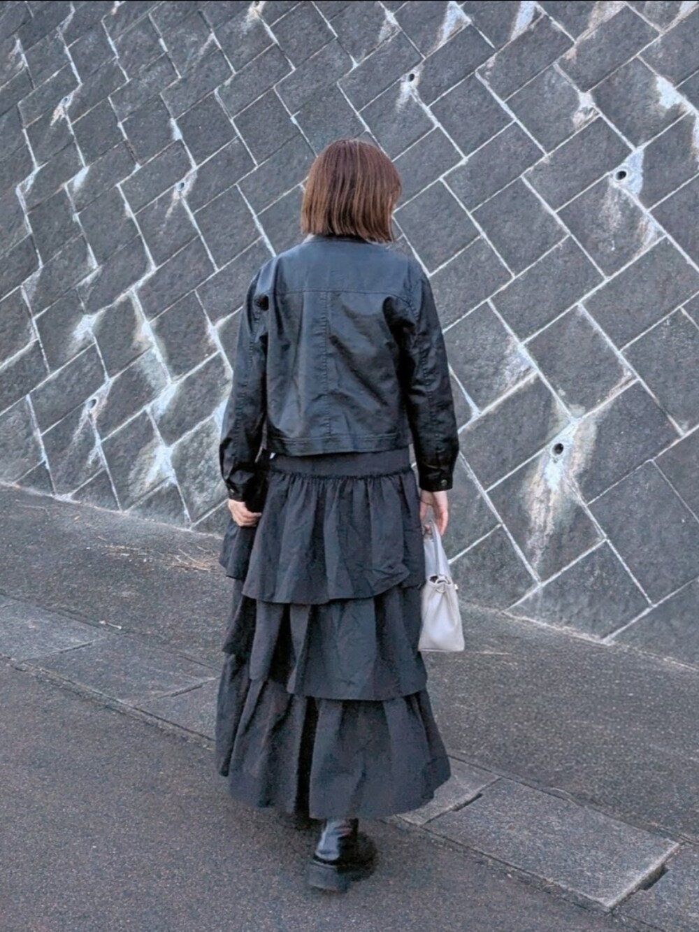 ブラック系のブルゾン、ブラック系のスカート、ホワイト系のTシャツ/カットソーを着用したレディースの冬コーディネートの3枚目の写真