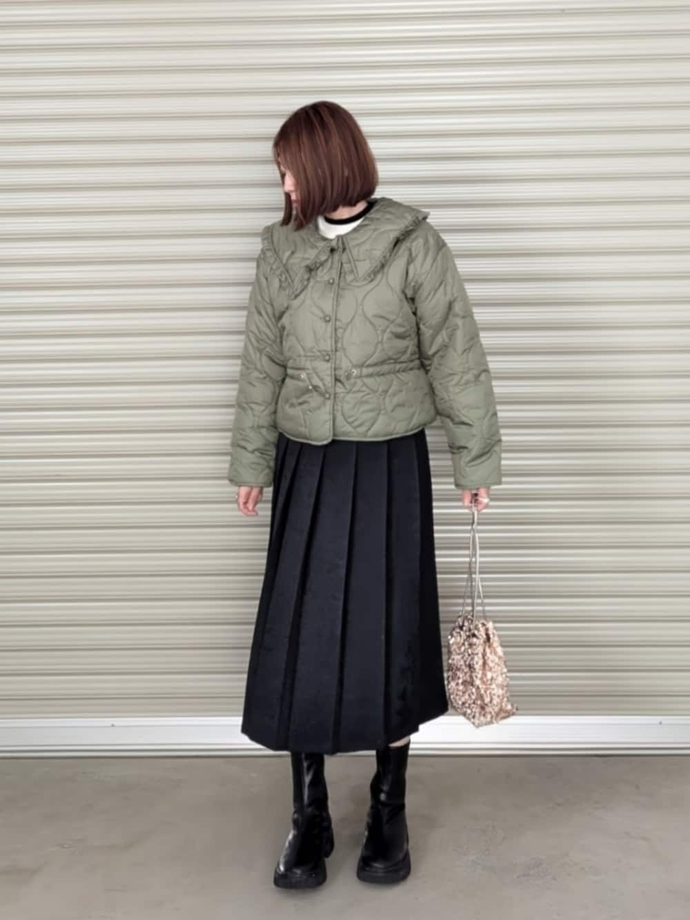 グリーン系のダウンジャケット/コート、ホワイト系のニット/セーター、ブラック系のブーツを着用したレディースの秋コーディネートの5枚目の写真