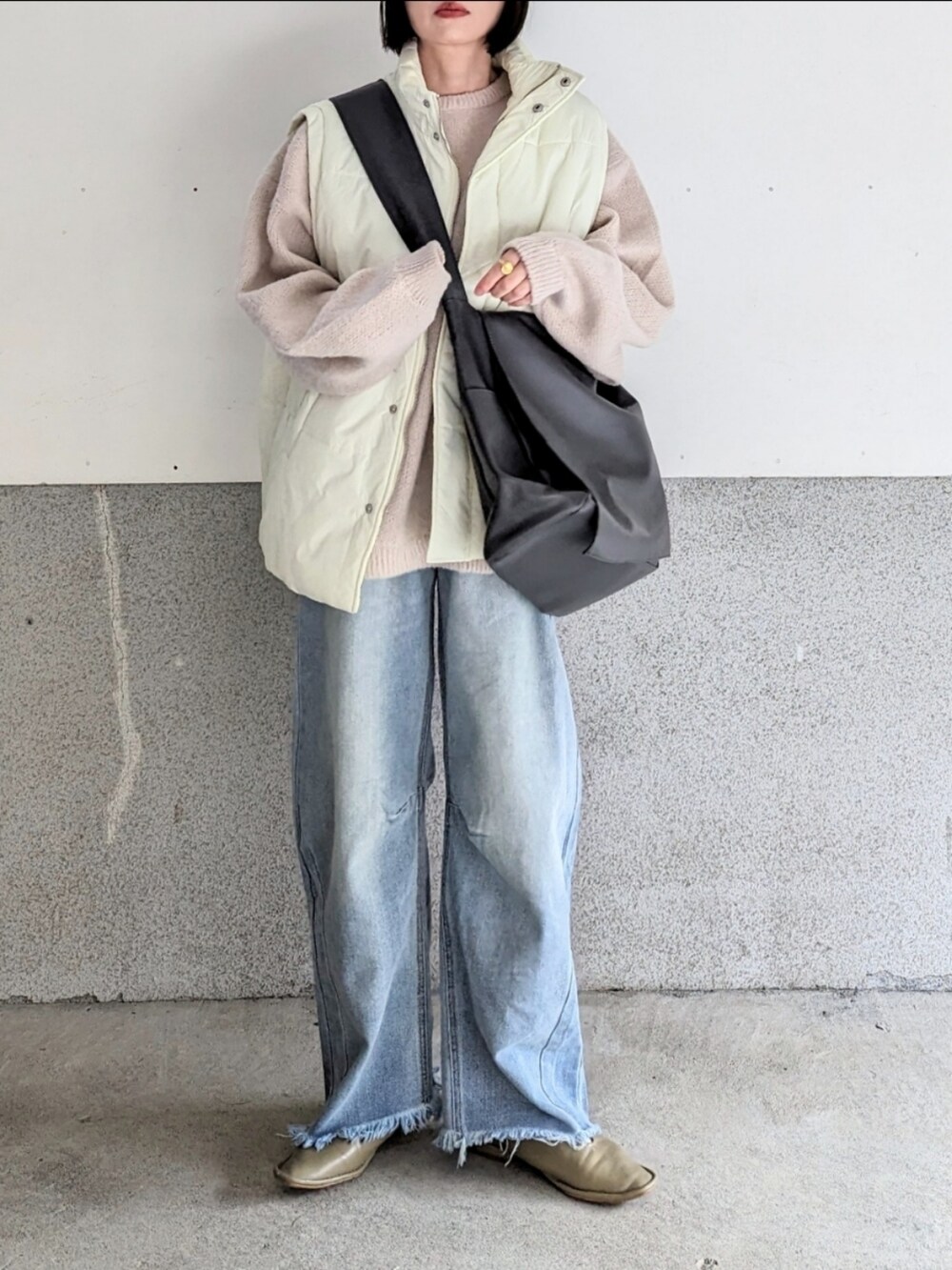 ベージュ系のニット/セーター、ホワイト系のダウンベスト、ブルー系のデニムパンツを着用したレディースの秋コーディネートの2枚目の写真