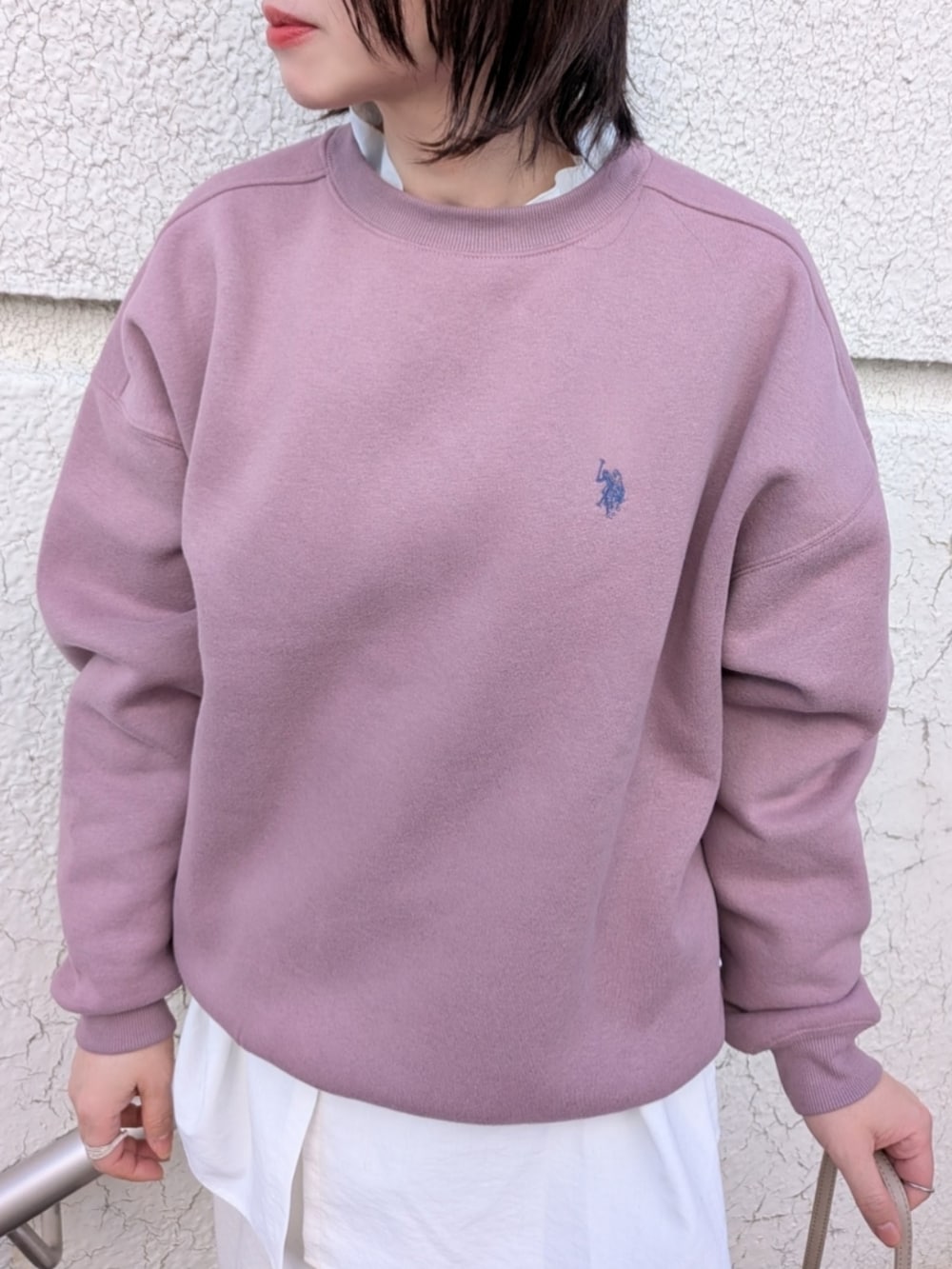 ピンク系のスウェット、ベージュ系のショルダーバッグ、ブラック系のブーツを着用したレディースの冬コーディネートの3枚目の写真