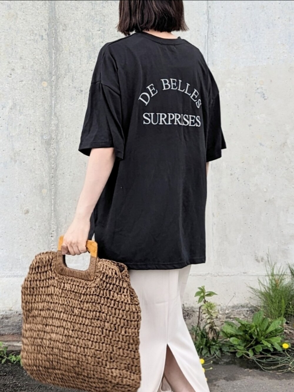 ブラック系のTシャツ/カットソー、ホワイト系のスカート、ブラウン系のかごバッグを着用したレディースの夏コーディネートの2枚目の写真