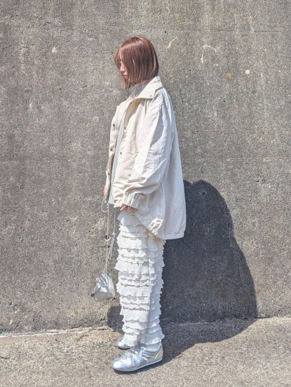 ホワイト系のナイロンジャケット、グリーン系のスウェット、ホワイト系のスカートを着用したレディースの春コーディネートの2枚目の写真