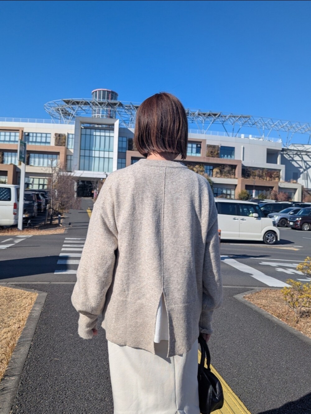 ベージュ系のニット/セーター、ホワイト系のTシャツ/カットソー、ホワイト系のスカートを着用したレディースの冬コーディネートの3枚目の写真