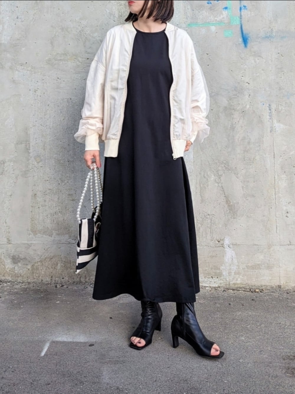 ホワイト系のブルゾン、ブラック系のワンピース、ホワイト系のショルダーバッグを着用したレディースの春コーディネートの2枚目の写真
