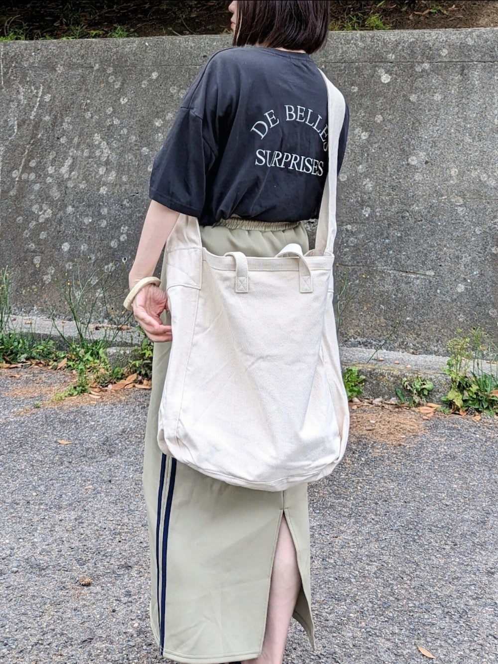 ブラック系のTシャツ/カットソー、ブルー系のスカート、ベージュ系のショルダーバッグを着用したレディースの春コーディネートの2枚目の写真