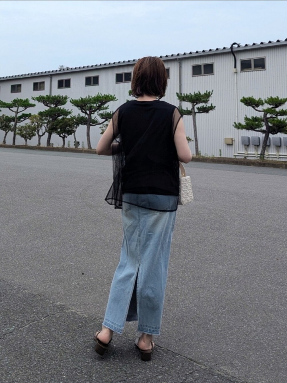 ブラック系のTシャツ/カットソー、ブルー系のスカート、ホワイト系のハンドバッグを着用したレディースの夏コーディネートの3枚目の写真