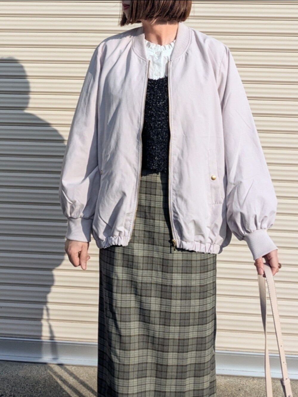 グレー系のブルゾン、ホワイト系のシャツ/ブラウス、ブラック系のベストを着用したレディースの秋コーディネートの2枚目の写真