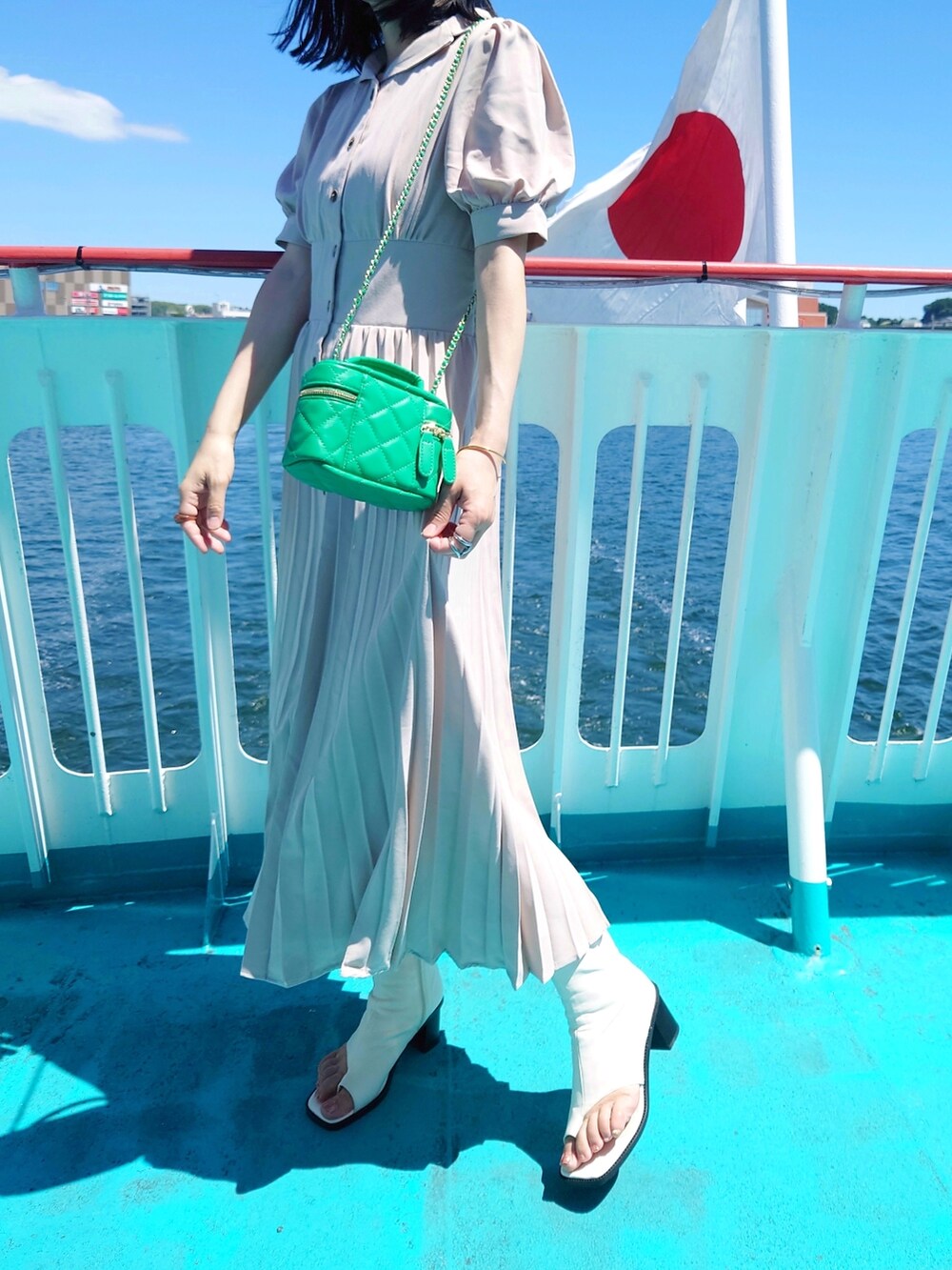 ベージュ系のシャツワンピース、グリーン系のショルダーバッグ、ホワイト系のサンダルを着用したレディースの夏コーディネートの2枚目の写真