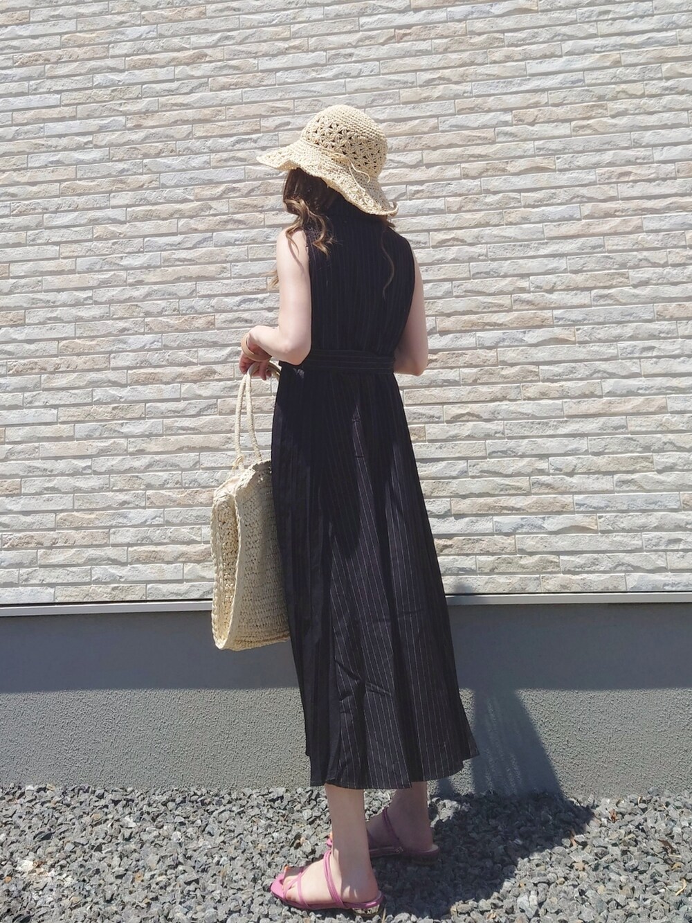 ブラック系のシャツワンピース、イエロー系のサンダル、ベージュ系のかごバッグを着用したレディースの夏コーディネートの2枚目の写真