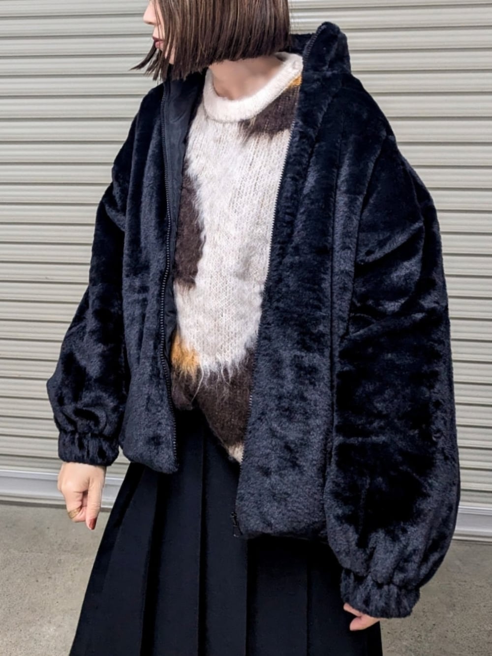 ブラック系のブルゾン、ブラウン系のニット/セーター、ブラック系のブーツを着用したレディースの秋コーディネートの2枚目の写真