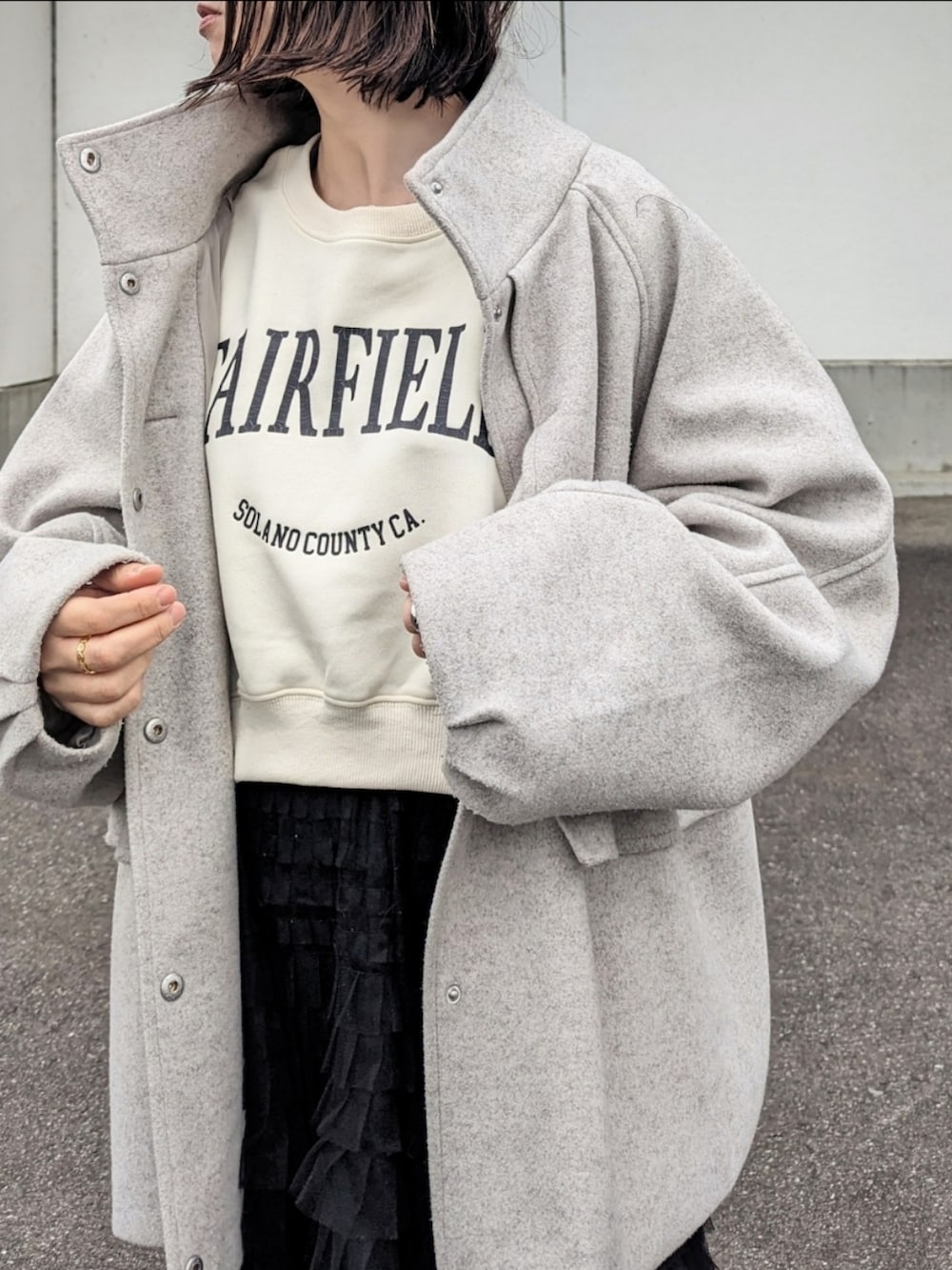 ホワイト系のスウェット、グレー系のその他アウター、ホワイト系のボストンバッグを着用したレディースの冬コーディネートの2枚目の写真